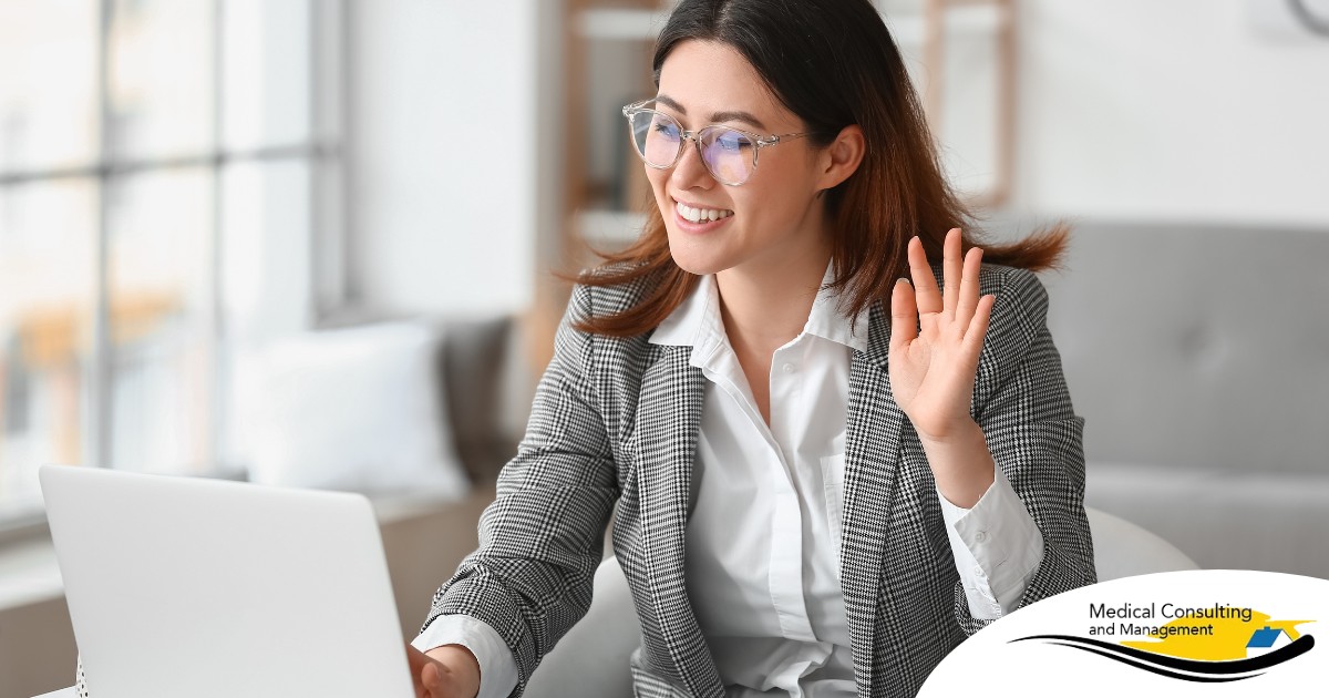 A well-dressed woman smiles and says hi on a videoconference, representing a candidate who is well-prepared for a caregiver interview.