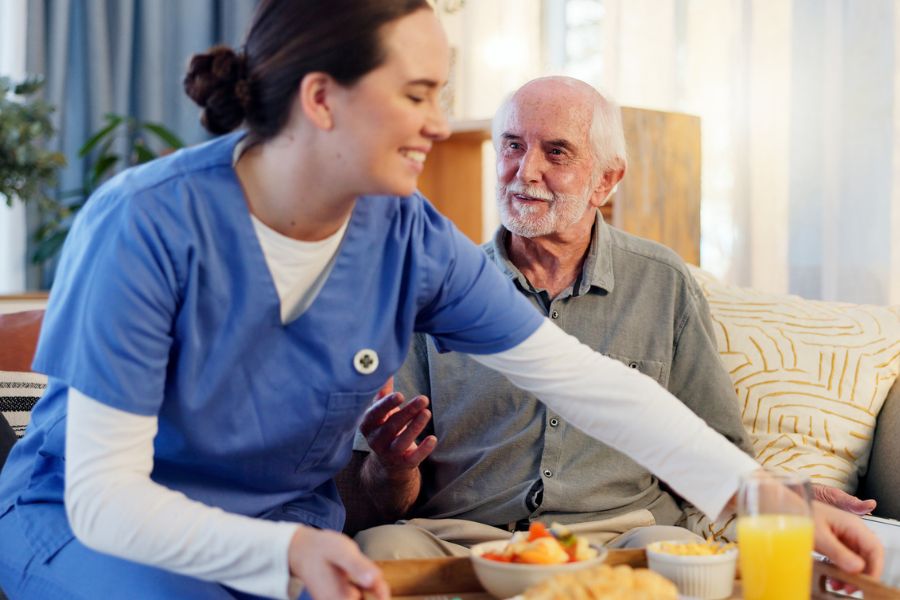 Caregiver serving meal to senior at home, representing meal preparation in Rockville