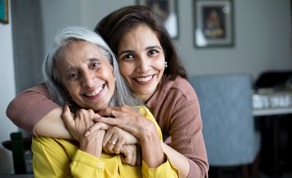 A smiling caregiver hugging a senior woman at home, representing light housekeeping in Rockville, MD